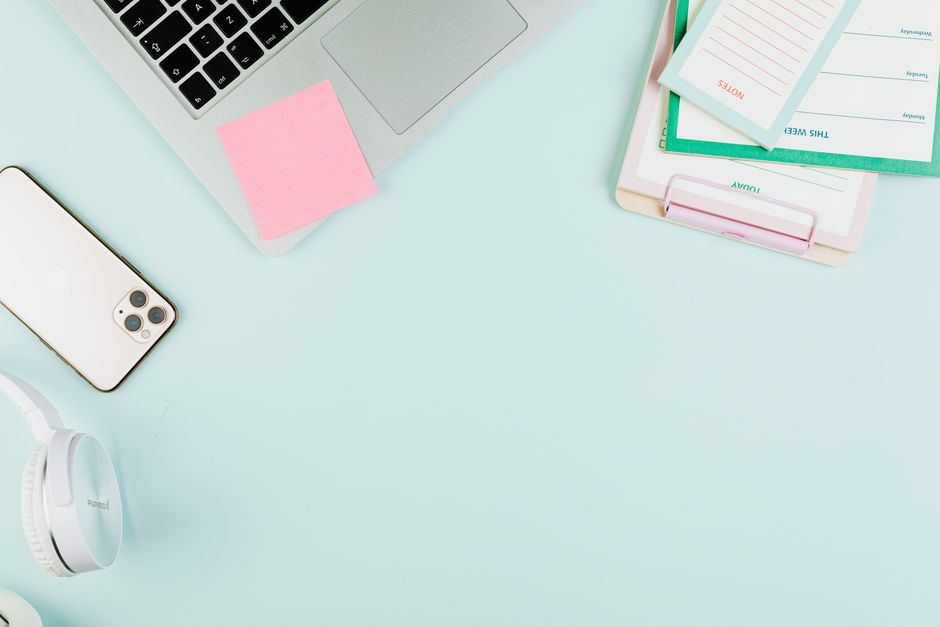 A clean, organized workspace featuring a laptop, smartphone, stationery, and headphones. Ideal for business themes.